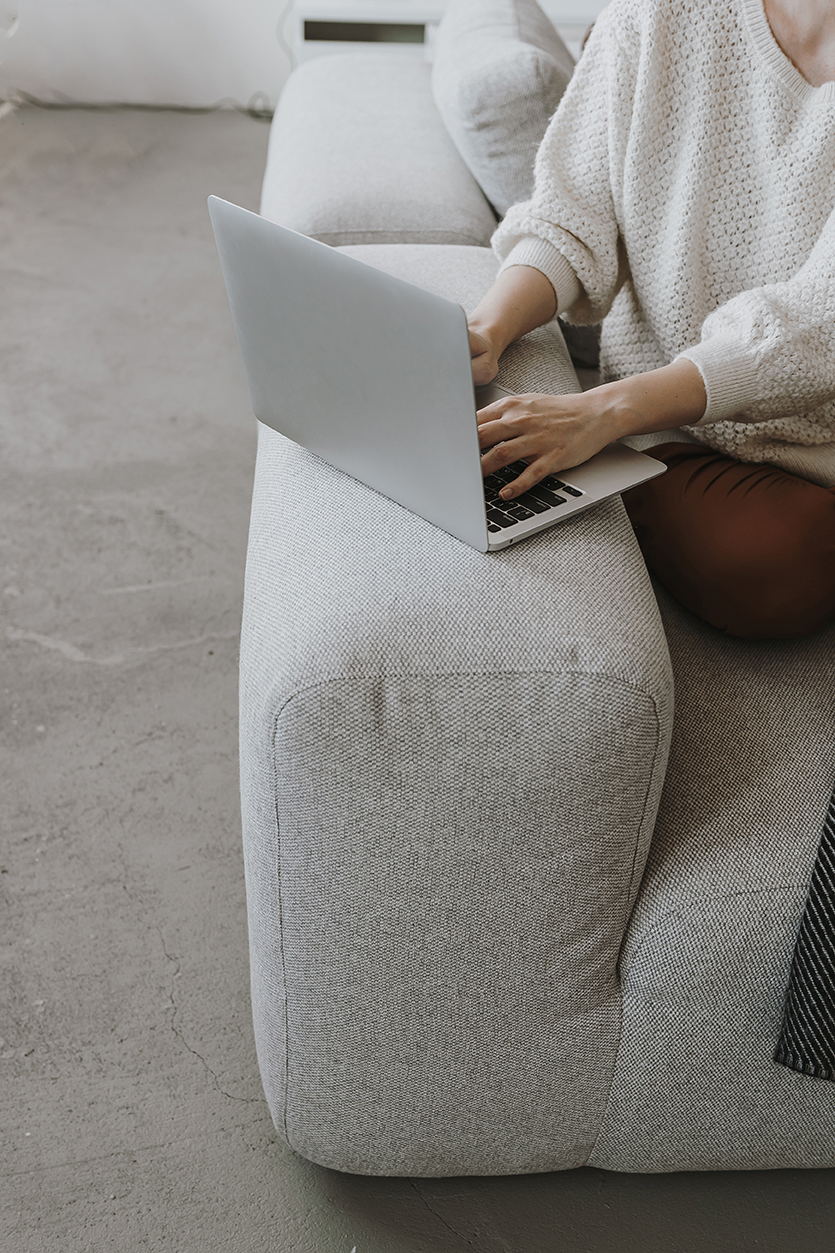 Young woman works laptop sitting comfortable sofa elegant person hands working laptop computer aesthetic bohemian home office workspace work home flat lay top view